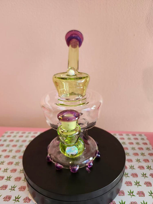 Mac Savage Urn Rig Green Purple glass dab rig shown in full front view highlighting its urn-shaped chamber with green and purple color accents