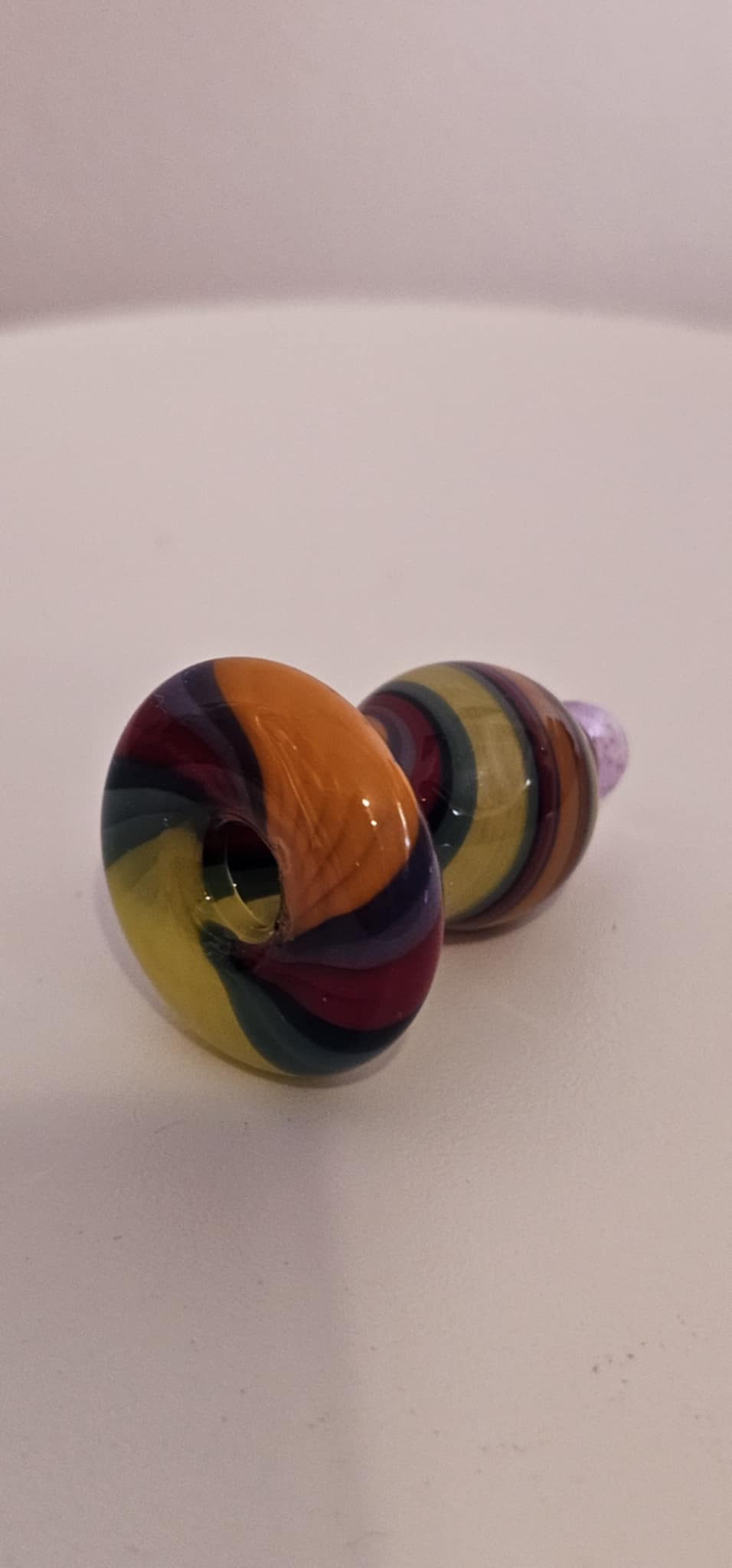 hand placing a colorful glass bubble carb cap onto a quartz banger on a dab rig during a dabbing session