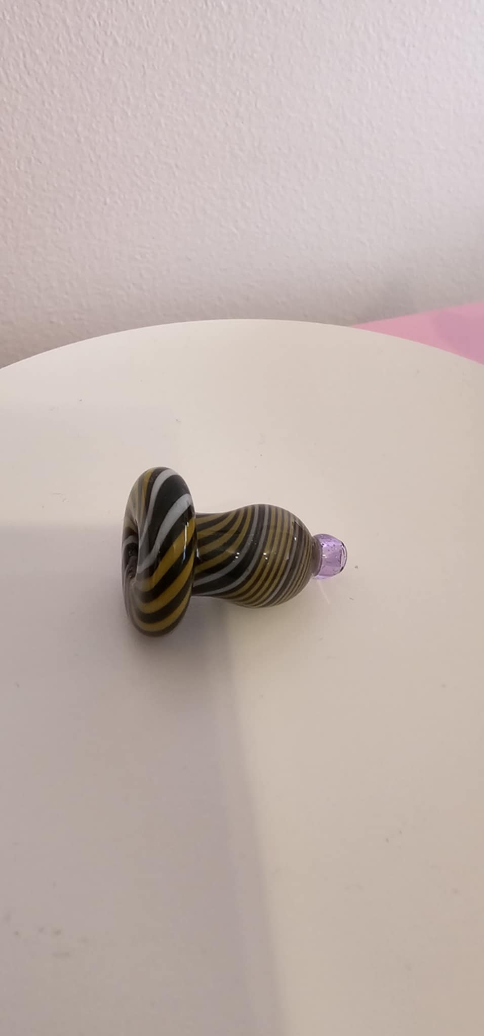 hand placing glass bubble carb cap on heated quartz banger while using dab rig on a clean surface