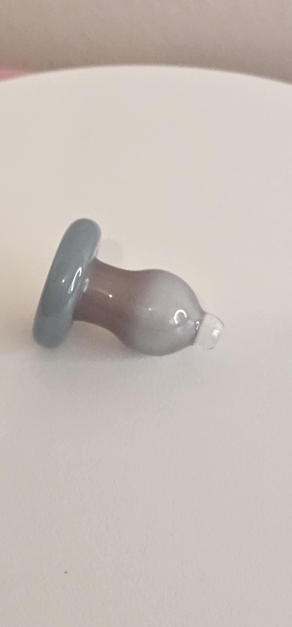 Close-up of glass bubble carb cap showing internal airflow channel and smooth gray swirl glass texture