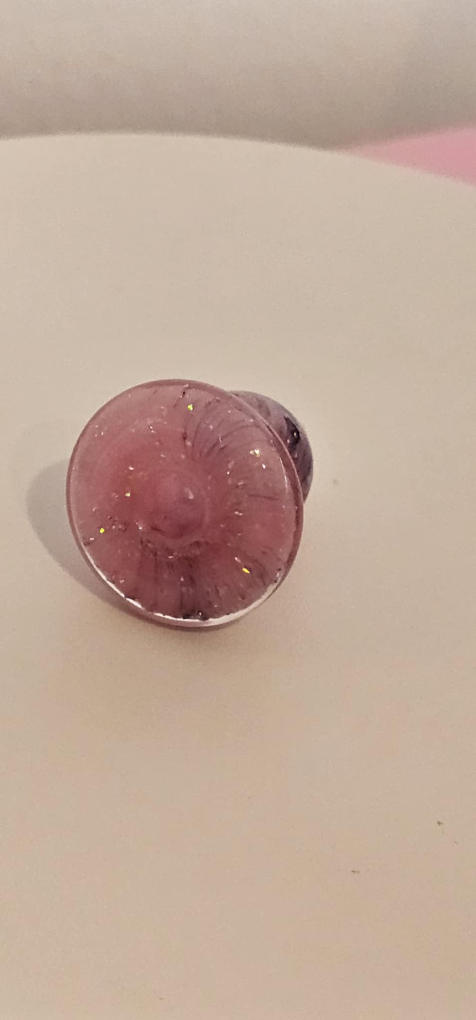 Close-up of glass carb cap highlighting pink and purple sparkle finish with smooth rounded bubble shape and airflow opening